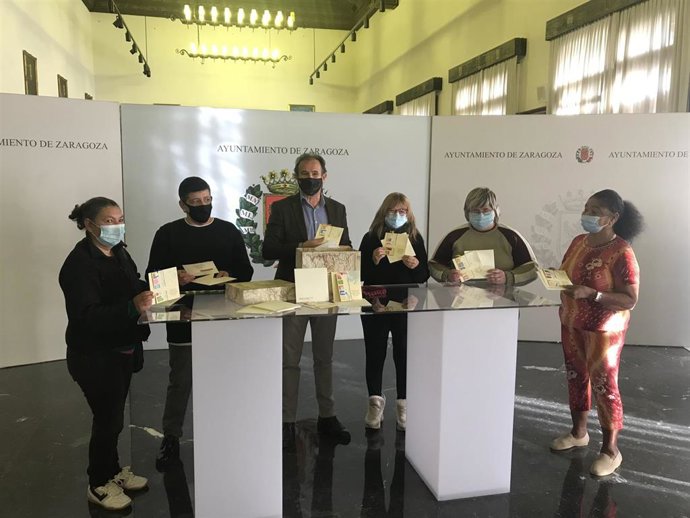 El consejero de Accíón Social del Ayuntamiento de Zaragoza, Ángel Lorén, con algunas de las participantes del taller de manualidades del albergue municipal que ha elaborado la tarjeta de Navidad