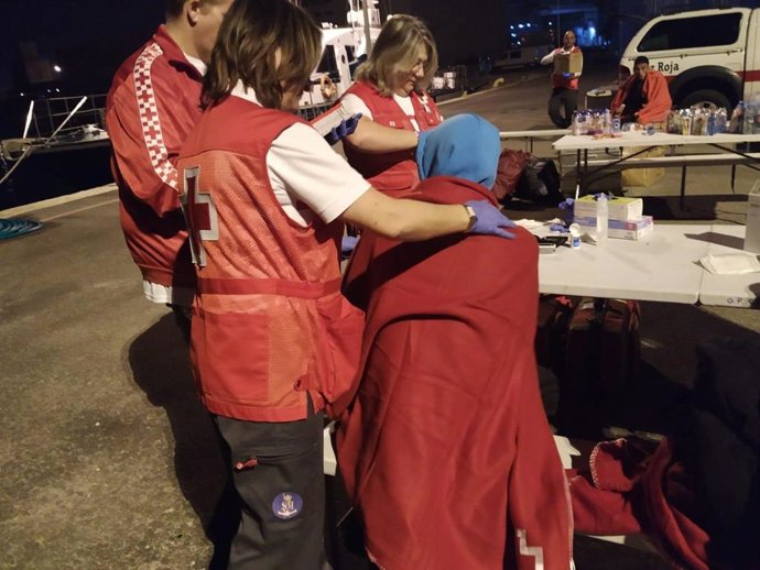Miembros de Cruz Roja atienden a una persona que ha llegado en una de las tres pateras