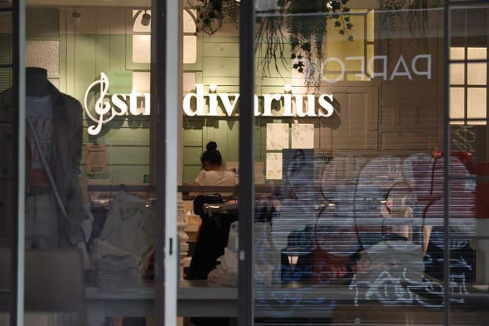 Una trabajadora protegida con mascarilla coloca los productos en una tienda de Stradivarius perteneciente a la marca Inditex que desde este jueves, algunas de sus tiendas de menos de 400 metros cuadrados de sus diferentes marcas en distintos puntos de l