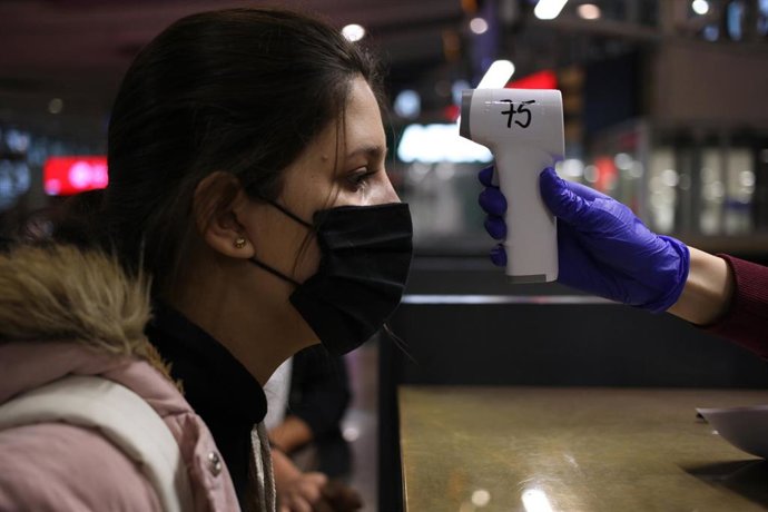 Una mujer colombiana se somete a un control de temperatura antes de abordar un avión de regreso a su país desde Santiago de Chile.