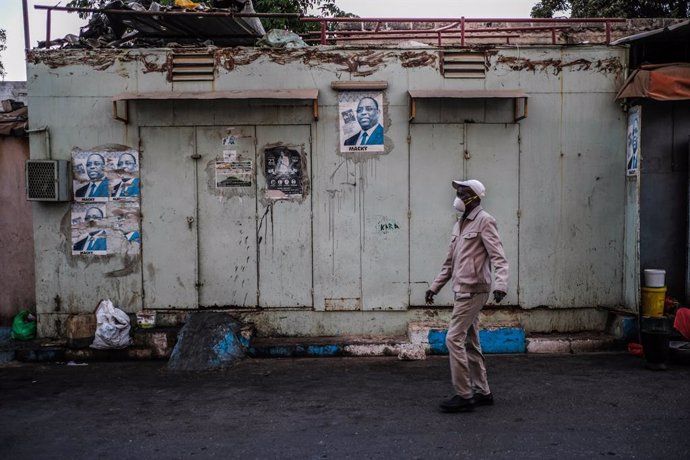 Un hombre camina junto a una tienda cerrada a causa de la pandemia de coronavirus en la capital de Senegal, Dakar