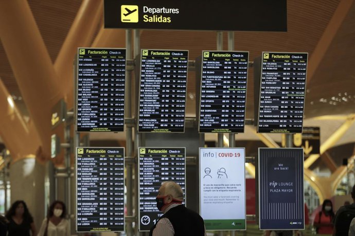 Pasajeros junto a páneles de información en la Terminal T4 del aeropuerto Adolfo Suárez Madrid-Barajas.