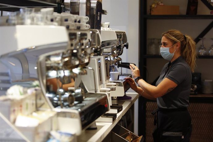 Una camarera sirviendo café en un bar.