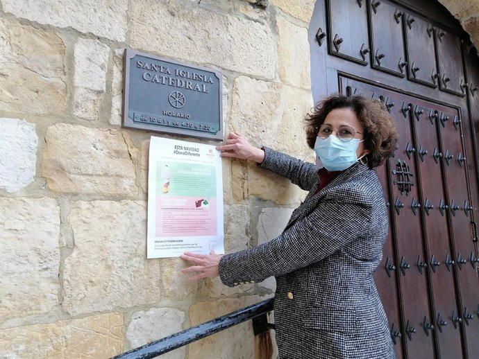 La directora de Cáritas, Sonsoles López, colocando un cartel en la entrada de la Catedral de Santander