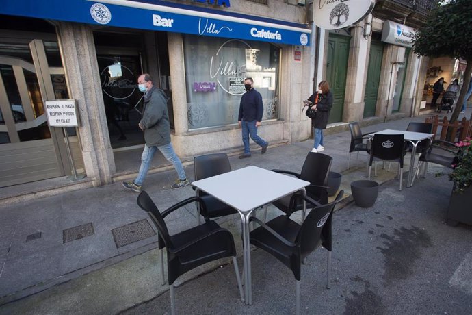Una cola de clientes espera a recoger un producto de un establecimiento cerrado en Vilalba, Lugo.