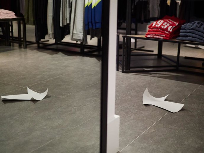 Detalle de los carteles informativos y señales de suelo del interior de una tienda de moda e Pamplona.