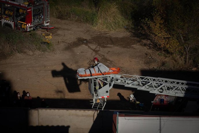 Bomberos retiran el cadáver de una de las personas fallecidas en el incendio de ayer en la nave okupada del barrio de Gorg, en Badalona, Barcelona, Catalunya (España), a 10 de diciembre de 2020. 