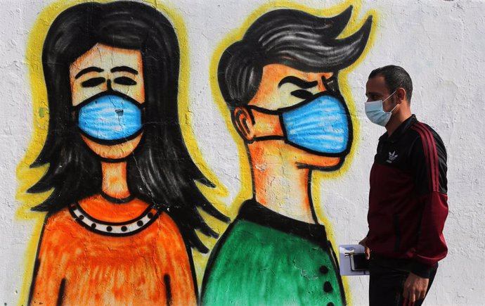 Un palestino con mascarilla pasa ante un mural en Deir al Balá, en la Franja de Gaza