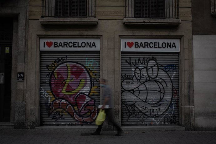 Un home camina al costat de dues botigues turístiques. Barcelona, Catalunya (Espanya), 16 de novembre del 2020. 