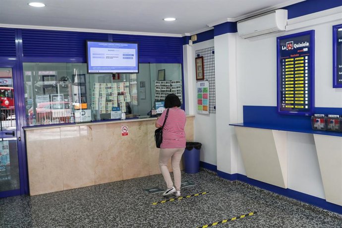 Una mujer compra lotería en una Administración de Loerías