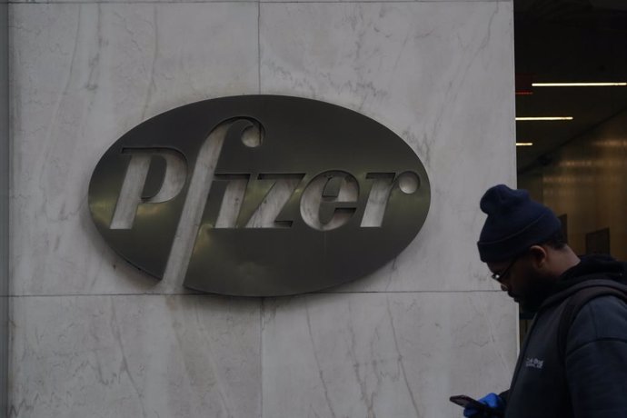 11 December 2020, US, New York: A man with a face mask walks past the headquarters of Pfizer Inc. The USFood and Drug Administration (FDA) is moving closer to approving emergency use of a Coronavirus (Covid-19) vaccine produced by Pfizer and BioNTech. 