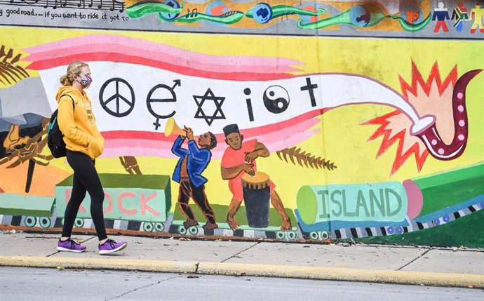 Una estudiante con mascarilla pasea frente a un mural en Rock Island, en Estados Unidos