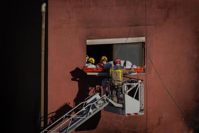 Bomberos retiran el cadáver de una de las personas fallecidas en el incendio de ayer en la nave okupada del barrio de Gorg, en Badalona, Barcelona, Catalunya (España), a 10 de diciembre de 2020. 
