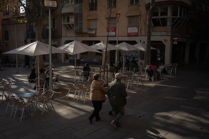 Dos mujeres caminan frente a una terraza durante el primer día del inicio del primer tramo de la desescalada de la segunda ola por el coronavirus en Barcelona.