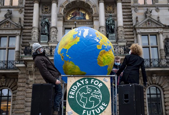 11 December 2020, Hamburg: Activists of "Fridays for Future" carry a ballon in the shape of the earth while building a so-called "Gallery of Failure" on the Hamburg City Hall Market on the nationwide day of action to commemorate the 1.5-degree target fo