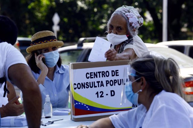 Una mujer mete en la urna su papeleta en la consulta popular organizada por la oposición en Venezuela. 