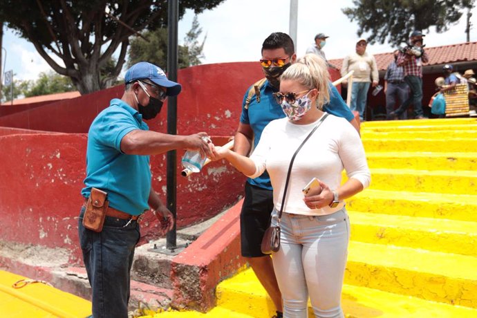 21 August 2020, Mexico, Mexico City: Aworker disinfects the hands of a visitor before boarding one of the Trajineras, the colorful boats of Xochimilco. The popular tourist spot of Xochimilco canals reopened on Saturday, after months of closure due to t