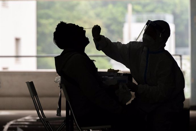 12 December 2020, China, Hong kong: A health worker takes a swab sample from a man at a Covid-19 testing centre in Hong Kong. Photo: Geovien So/SOPA Images via ZUMA Wire/dpa