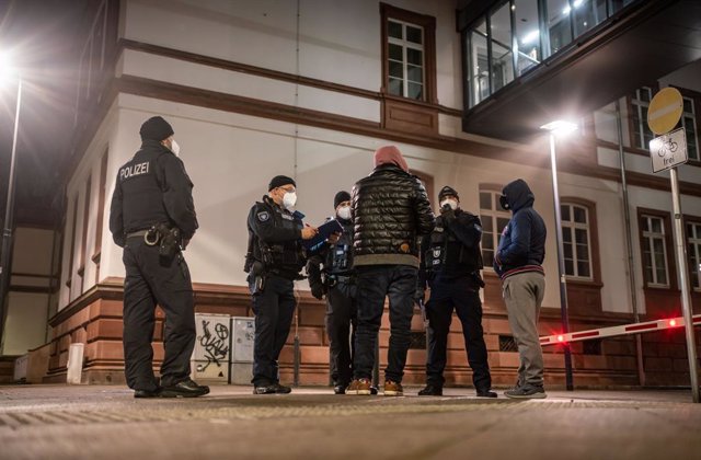 12 December 2020, Offenbach: Police officers record the personal details of two men amid night-time restrictions imposed for the first time due to high coronavirus numbers. The restrictions apply from 21:00 hrs to 05:00 hrs. Photo: Frank Rumpenhorst/dpa