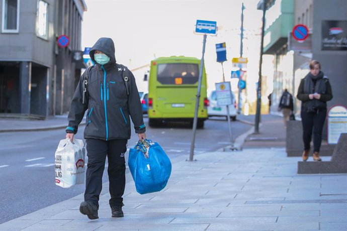 13 March 2020, Norway, Oslo: A man wearing a surgical mask walks through the streets of Oslo with shopping bags amid the coronavirus outbreak. Photo: Hkon Mosvold Larsen/scanpix/dpa