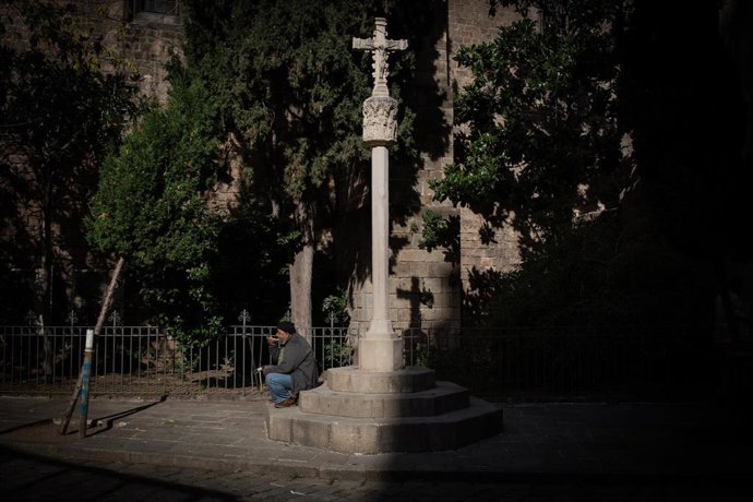 Una persona sin techo come en el exterior de las instalaciones del Hospital de campaña instalado en la parroquia de Santa Anna.