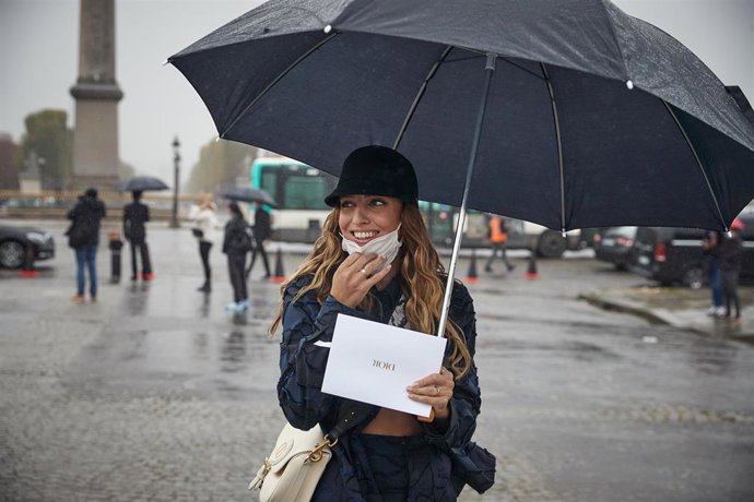 Una mujer con mascarilla y paraguas en París, Francia