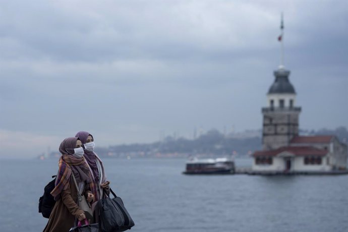Dos mujeres con mascarilla pasean ante la Torre de la Doncella en Estambul