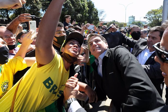 HANDOUT - 26 August 2020, Brazil, Ipatinga: Brazilian President Jair Bolsonaro (R) poses for pictures with his supporters upon arrival for a ceremony to resume operations of the blast furnace of steel company Usiminas for the first time since the covid-