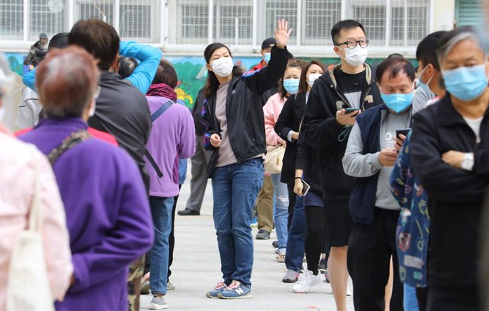 Un grupo de residentes de uno de los edificios en los que se ha localizado un último brote de la COVID-19 en Hong Kong hace turno para someterse a una prueba de coronavirus.