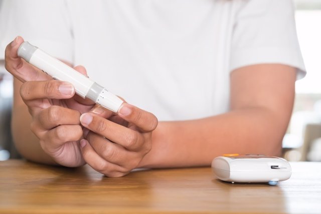 Close up of asian woman hands using lancet on finger to check blood sugar level by glucose meter, Healthcare medical and check up, diabetes, glycemia, and people concept