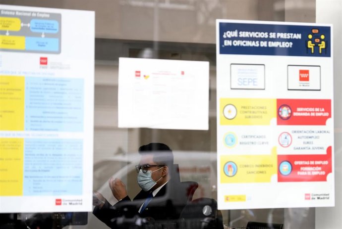 Un hombre con mascarilla tras el cristal de la puerta de una oficina de empleo, SEPE (antiguo INEM)