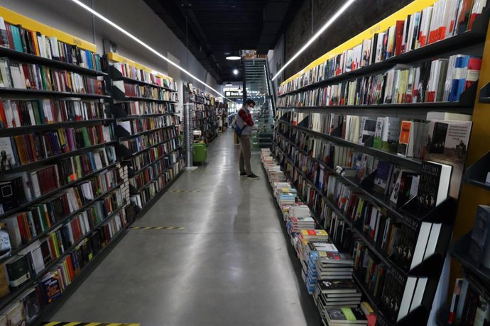 Una persona ojea libros en una librería 
