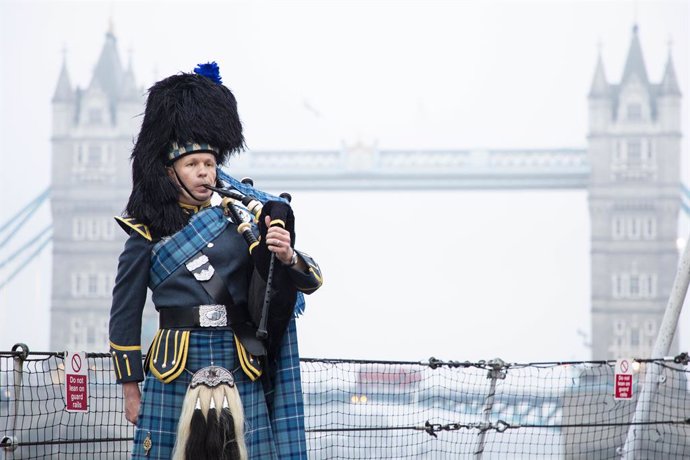 HANDOUT - 15 August 2020, England, London: Pipe Sergeant Neil Esslemont of RAF Halton Pipes & Drums plays in front of the Tower Bridge on the 75th anniversary of the Victory over Japan Day. Photo: Po Phot Dave Jenkins/Mod via PA Media/dpa - ATTENTION: e