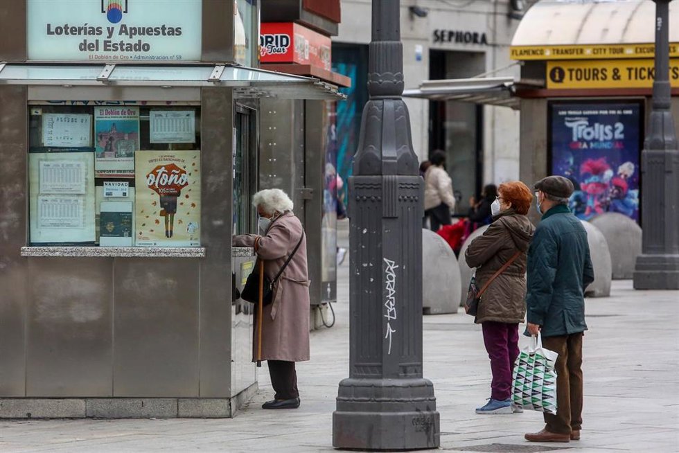 Varias personas hacen cola en las inmediaciones de una administración de la Puerta del Sol donde venden boletos para el Sorteo Extraordinario de la Lotería de Navidad 2020, en Madrid (España), a 4 de noviembre de 2020. A un mes y medio del tradicional s