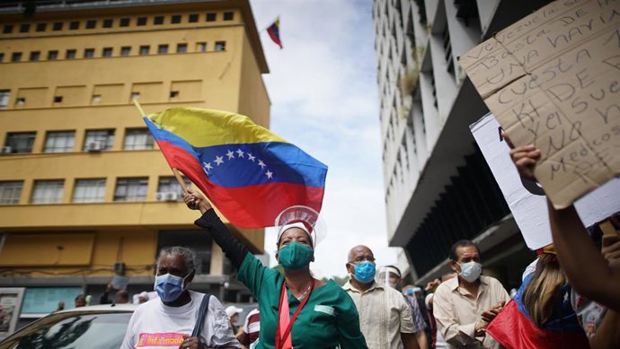Una trabajadora del sector sanitario ondea una bandera de Venezuela durante una protesta para pedir mejores condiciones a los sanitarios durante la pandemia del coronavirus.