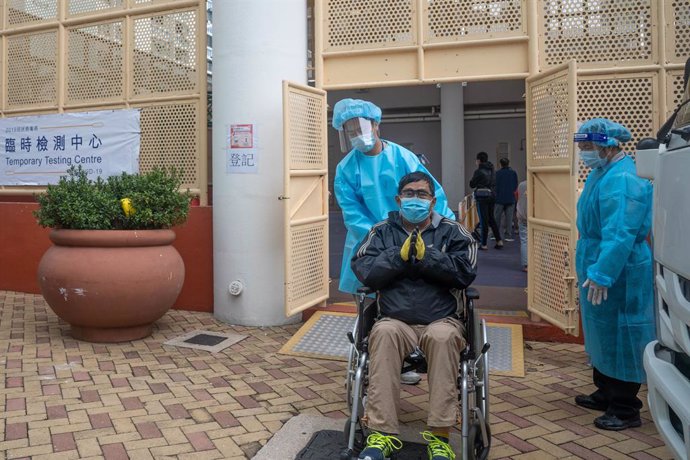 16 December 2020, China, Hong Kong: A health worker in Personal Protective Equipment assists a disabled man in a wheelchair at a makeshift coronavirus (COVID-19) testing centre near a public housing estate. Photo: Geovien So/SOPA Images via ZUMA Wire/dpa