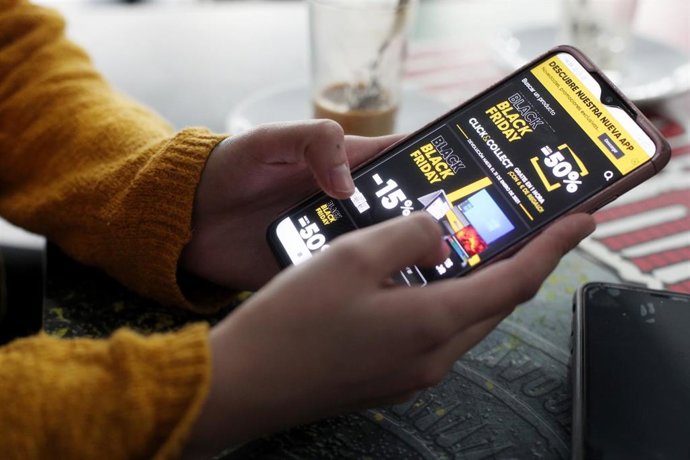Una joven consulta las ofertas de Black Friday de un comercio en su móvil.