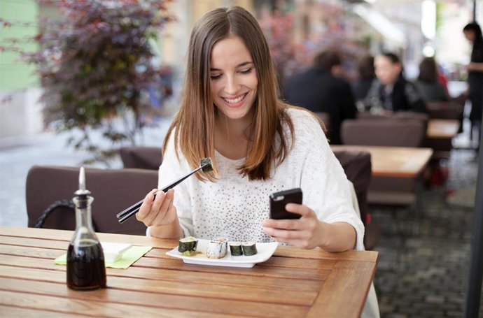 Joven comiendo sola en un restaurante.