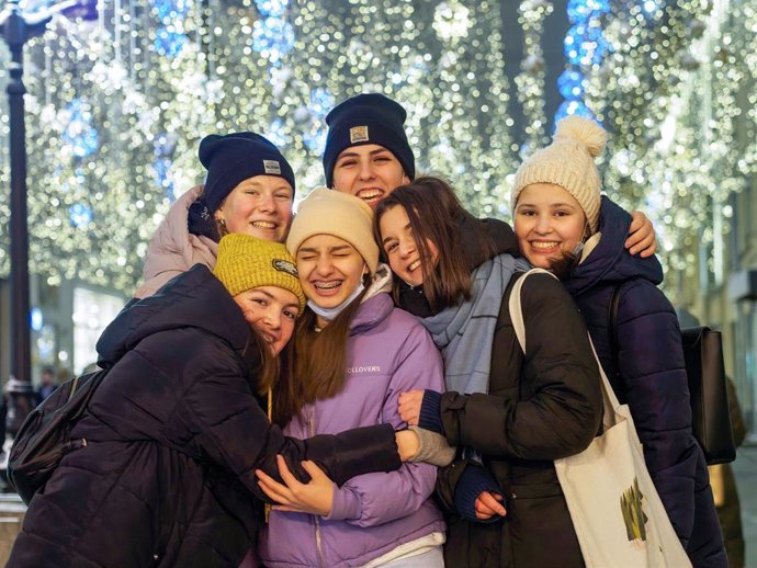 Varias personas posan sin mascarilla ante las luces navideñas en Moscú