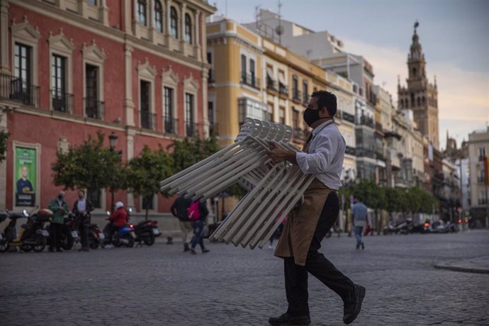 Un hostelero recoge el mobiliario de la terraza de un bar, foto de recurso