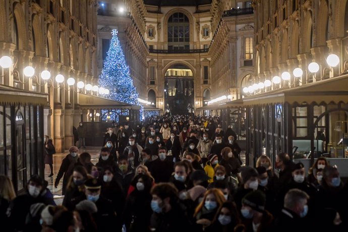 Ciudadanos con mascarilla haciendo compras navideñas en Milán