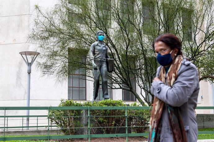 Una mujer pasa frente a una estatua con mascarilla en Montevideo, acción promovida por el Gobierno para fomentar el uso de mascarilla.