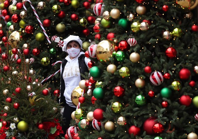 16 December 2020, England, London: A woman stands amongst a festive display outside a restaurant at Kensington High Street in London which has been placed in the highest level of coronavirus restrictions due to rising case numbers. Photo: Yui Mok/PA Wir