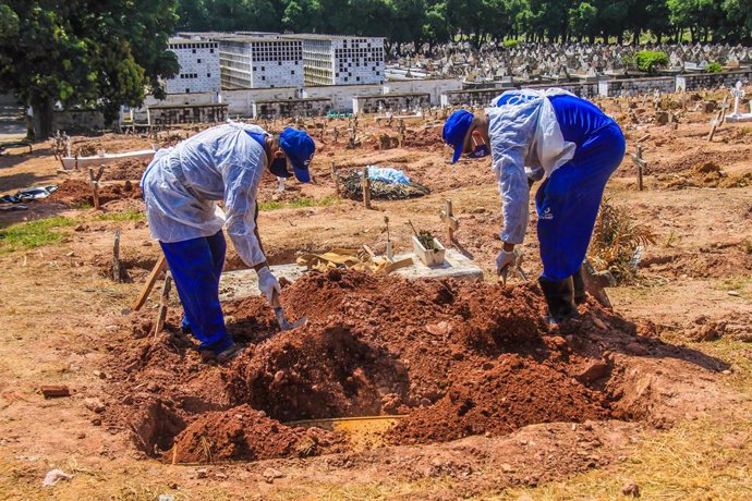 16 December 2020, Brazil, Rio de Janeiro: Cemetery workers in protective suits bury the body of a man who died from the coronavirus (COVID-19) at Sao Francisco Xavier cemetery. Photo: Ellan Lustosa/ZUMA Wire/dpa