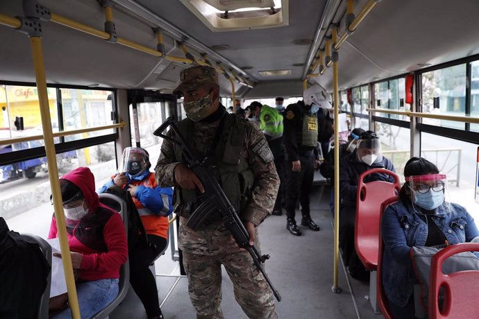 Un grupo de policías realizando labores de vigilancia y comprobando los permisos de circulación en un autobús de Lima, en medio de la crisis sanitaria provocada por la pandemia.