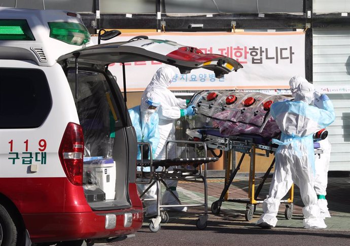 17 December 2020, South Korea, Ulsan: Medical workers clad in protective gear carry a patient infected with the coronavirus (COVID-19) onto an ambulance at an elderly care facility Photo: -/YNA/dpa