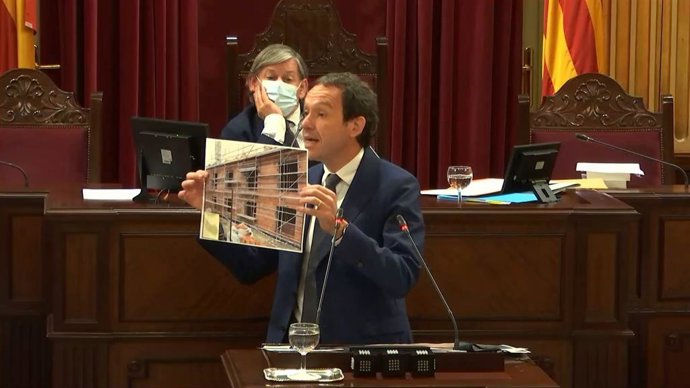 El conseller Marc Pons enseña al PP imágenes de las promociones en marcha, durante el debate de presupuestos de 2021.
