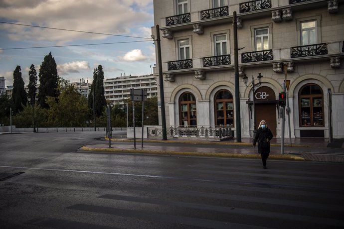 07 November 2020, Greece, Athens: A woman wearing a face mask crosses an empty street at the start of a three week national lockdown for Greece. Greek Prime Minister Kyriakos Mitsotakis said on Thursday that he has ordered the country's second lockdown 
