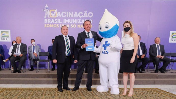 HANDOUT - 16 December 2020, Brazil, Brasilia: Brazilian President Jair Bolsonaro (2nd L) poses for a photo with the mascot Ze Gotinha, a traditional character in Brazil created to raise awareness about the coronavirus vaccines, during the launch of the 