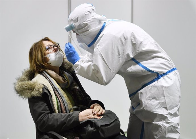 10 December 2020, Austria, Eisenstadt: A health worker takes a swab from a woman for coronavirus test at the All Sports Centre. Photo: Robert Jaeger/APA/dpa
